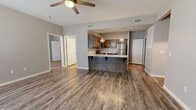 This 1-bedroom, 1-bathroom residence is thoughtfully laid out across a single floor, making efficient use of its space. The open-concept living and kitchen area serves as the heart of the home, featuring durable hardwood-style plank flooring, neutral gray walls, and a ceiling fan that adds both style and function. Natural light filters in through windows fitted with horizontal blinds, creating a bright and welcoming atmosphere.

The kitchen is a standout feature, equipped with stainless steel appliances including a refrigerator, range, microwave, and dishwasher. Rich, dark wood cabinetry pairs with a herringbone tile backsplash and light granite countertops for a modern aesthetic. A peninsula with an overhang and pendant lighting above provides casual seating and additional prep space.

The bedroom offers a comfortable retreat, finished with plush carpet flooring, a ceiling fan, and a large window that brings in natural light. An adjacent closet provides dedicated storage. The bathroom is cleanly appointed with a tub/shower combo, a granite-topped vanity with matching wood cabinetry, and the same hardwood-style flooring found throughout the main living areas. A hallway connects the private spaces seamlessly to the main living area.