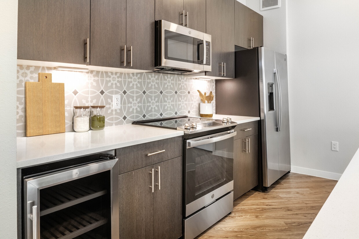 Cocinas con electrodomésticos de acero inoxidable, refrigeradores para vinos, encimeras de cuarzo, salpicadero de azulejos y pisos de superficie dura. - Avalon Townhomes Bee Cave