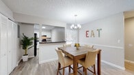 This single-floor residence offers a thoughtfully designed layout that balances comfort and functionality. Light gray walls, light-toned wood-look flooring, and textured ceilings create a cohesive, neutral palette throughout the home.

The spacious living room serves as the heart of the home, featuring a ceiling fan, wainscoting, and a large sliding glass door that floods the room with natural light and provides access to an outdoor patio area. The adjoining dining area is defined by an elegant chandelier and flows seamlessly into the kitchen via a pass-through counter, making it ideal for entertaining.

The kitchen is equipped with white shaker-style cabinetry, dark granite countertops, a tile mosaic backsplash, and black appliances including a refrigerator, range, and dishwasher. A window above the sink brings in additional natural light.

The bedrooms are generously proportioned, each featuring windows with natural light and light wood-look flooring. One bedroom showcases a warm, rustic aesthetic with a wooden headboard and dresser, while another presents a bright, welcoming feel with corner windows.

The bathroom is clean and functional, featuring a white vanity with ample counter space, a tub-shower combination, and tasteful neutral finishes that complete the home's consistent design language.
