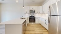 Located in the Shadow Creek community of Jackson, Tennessee, this two-story home presents a clean, modern aesthetic carried consistently across both levels. Light wood-style luxury vinyl plank flooring runs throughout the living areas, complementing the neutral warm-white wall tones and crisp white trim to create a bright, cohesive interior.

The kitchen is a functional centerpiece, outfitted with white shaker-style cabinetry featuring matte black hardware, quartz countertops, a stainless steel undermount sink, and stainless steel appliances including a range and over-the-range microwave. Pendant lighting adds a contemporary accent above the counter space.

The upper level, accessible via an open staircase, features a ceiling fan and angled architectural lines that add visual interest to the upper-floor layout. Bedrooms receive generous natural light through large windows fitted with horizontal blinds, with vaulted or angled ceiling details enhancing the sense of space.

The bathrooms are well-appointed, each featuring dark-stained vanities with white countertops, framed mirrors, contemporary light fixtures, and coordinating matte black hardware. One bathroom includes a tub-shower combination, while another offers additional vanity storage and a towel bar. Clean lines and consistent finishes reinforce the home's polished, move-in-ready presentation.