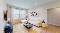 Located at 1020 Larsen Rd in Jackson, NJ, this thoughtfully designed single-floor residence offers a seamless open-concept layout that connects the living, dining, and kitchen areas into one cohesive and welcoming space. Light wood-tone flooring runs throughout, complementing the neutral, warm color palette that defines the home's modern aesthetic.

The kitchen is a standout feature, equipped with stainless steel appliances including a gas range, microwave, dishwasher, and full-size refrigerator. Flat-front cabinetry in a warm taupe finish extends to the ceiling for ample storage, while a white quartz island with pendant globe lighting serves as both a prep surface and casual dining area with bar seating. A subway tile backsplash adds a clean, contemporary touch.

The open dining area sits adjacent to the kitchen and leads directly to a private balcony through sliding glass doors, allowing natural light to fill the space. The living room features recessed lighting, large windows with outdoor views, and generous proportions ideal for relaxed entertaining.

The primary bedroom is a serene retreat with large windows, light-filtering treatments, and light wood flooring. A second bedroom functions well as a home office, also benefiting from natural light. The bathroom is finished with large-format tile flooring, a floating wood vanity, and a clean, minimalist design throughout.