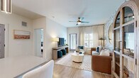 Located at 7222 S Peek Rd in Houston, TX, this thoughtfully designed 2-bedroom, 2-bathroom residence offers a well-appointed single-floor layout that blends contemporary style with everyday comfort. Light wood-look flooring flows throughout, unifying the open-concept living, dining, and kitchen areas. The living room is a standout space, featuring a botanical-print accent wall, a ceiling fan, large windows with sheer drapery, and a glass-paneled exterior door that invites natural light. The kitchen is equipped with white shaker cabinetry, black hardware accents, stainless steel appliances including a side-by-side refrigerator, a breakfast bar island with a built-in sink, and a built-in wine rack. The adjacent dining area features whimsical bird-motif wallpaper, adding a playful design touch near the entryway. The primary bedroom is generously proportioned, offering a ceiling fan, bright windows, and access to an en-suite bathroom complete with a marble-tiled glass-enclosed shower, a wide vanity with white cabinetry and black fixtures, and a walk-in closet. The second bedroom is equally bright and comfortable, with large windows and warm neutral tones. Throughout the residence, curated wallpapers, designer lighting, and cohesive finishes create a polished and welcoming ambiance.