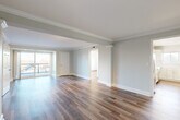 Located at 190 N Shore Rd in Revere, MA, this well-appointed 2-bedroom, 2-bathroom residence offers a thoughtfully designed single-floor layout with an open, airy feel throughout. The expansive living room is a standout feature, showcasing warm hardwood-style flooring, elegant crown molding, decorative column accents, and track lighting. Large sliding glass doors lead to a private balcony, flooding the space with natural light and providing pleasant outdoor views. The kitchen is outfitted with shaker-style cabinetry, white quartz countertops, a subway tile backsplash, and stainless steel appliances including a refrigerator and dishwasher. The generously sized primary bedroom features dual windows that bring in ample natural light, while the second bedroom offers its own window with scenic tree-lined views and stylish wall sconces. Both bedrooms are finished with the same hardwood-style flooring seen throughout the home. The two bathrooms are cleanly designed, with one featuring a glass-enclosed walk-in shower with neutral tile surround and modern vanity fixtures. Three closets provide excellent storage throughout. Soft sage-green and neutral tones create a calm, cohesive ambiance across all rooms.