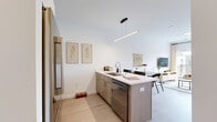 Located at 1601 Sherman Ave in Madison, WI, this thoughtfully designed one-bedroom, one-bathroom unit offers a smart, efficient layout across a single floor. Light hardwood flooring flows throughout, lending warmth and visual continuity to the space.

The open kitchen is a standout feature, equipped with stainless steel appliances including a French door refrigerator, range, and microwave. White upper cabinetry contrasts elegantly with wood-toned lower cabinets and light countertops. A peninsula with bar seating and a sleek linear pendant light above makes the kitchen ideal for casual dining and entertaining.

The bedroom is a calm, well-proportioned retreat featuring a large window that admits generous natural light, a ceiling fan, and direct access to a dedicated walk-in closet — providing practical storage. The clean white walls and light flooring give the room an airy, restful quality.

The bathroom is finished in a clean, contemporary style with light wood vanity cabinetry, a stone-look countertop, a framed mirror, and wood-look tile flooring that ties back to the rest of the unit's warm palette.

Overall, the unit offers a cohesive, modern aesthetic with neutral tones, quality finishes, and a functional layout well-suited for everyday living in Madison's vibrant Sherman Ave corridor.