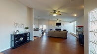 Located at 3245 E University Ave in Las Cruces, NM, this single-floor space offers a versatile and well-appointed layout designed for both comfort and function. Rich, dark hardwood flooring runs throughout, creating a cohesive and polished aesthetic across all areas.

The open main area is anchored by a classic fireplace with a white mantle, a wall-mounted television, and ceiling fans that complement the vaulted ceiling profile. Recessed lighting and large windows allow natural light to fill the space generously, contributing to a bright and welcoming ambiance.

A dedicated kitchenette area features a extended bar-height counter with seating for several, a compact refrigerator, and a coffee station — ideal for gatherings or day-to-day use. Adjacent to the kitchenette, a set of French doors opens to the exterior, enhancing the sense of openness and providing direct outdoor access.

A separate meeting or dining nook includes a round table with upholstered seating and its own set of French doors, offering a more intimate and private setting bathed in natural light. A dedicated workspace area accommodates a full desk setup, providing a productive environment within the broader layout.

Together, these features make this Las Cruces property a highly functional and inviting space suited for a variety of uses.