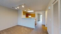 Located at 750 Nicklaus Blvd in Columbus, Ohio, this single-floor unit offers a well-designed, open-concept layout that maximizes functionality and comfort. The spacious living area is finished with plush wall-to-wall carpeting and a textured ceiling, while track lighting provides flexible illumination throughout. A large sliding glass door opens to a private balcony, inviting natural light and outdoor views into the main living space, complemented by an additional window for added brightness.

The kitchen features warm wood cabinetry, a peninsula with beadboard detailing that serves as a natural divider between the kitchen and living area, and white laminate countertops. Appliances include a refrigerator, dishwasher, and range, all set atop durable wood-look flooring. Recessed and under-cabinet lighting ensure the space is well-lit for everyday use.

The bedroom is generously sized and carpeted, with a sliding glass door leading to its own balcony access and outdoor views. An adjacent full bathroom offers wood-look flooring, a vanity with warm wood cabinetry, and a shower-tub combination. A dedicated utility area features built-in shelving and a clothes rod, providing ample organized storage. Throughout the unit, neutral tones create a cohesive and welcoming ambiance.