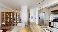 Located at 451 Hialeah Dr in Hialeah, FL, this thoughtfully designed single-floor studio offers a bright, open layout with clean modern finishes throughout. Light wood-tone flooring flows seamlessly across the entire space, complementing the crisp white walls and creating a warm, airy atmosphere.

The living area is well-defined by a freestanding open-cube wood shelving unit that acts as a stylish room divider, elegantly separating the sleeping area from the main living space. A ceiling fan overhead and track lighting add both function and character. Large sliding glass doors in the living area open to a private balcony, allowing abundant natural light to fill the interior.

The kitchen is outfitted with a full suite of stainless steel Whirlpool appliances, including a side-by-side refrigerator with water dispenser, electric range, and over-the-range microwave. Contemporary gray cabinetry extends to the ceiling and is paired with white subway tile backsplash and clean countertops, offering generous storage and prep space. A compact dining area sits adjacent to the kitchen, completing the entertaining zone.

The sleeping area is tucked behind the open shelving divider, providing a sense of privacy while maintaining the open feel of the studio. The bathroom features neutral tile, a tub-shower combination, and a modern vanity with white countertop.