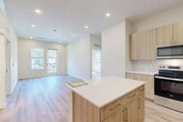 Located at 22632 E Radcliff Loop in Aurora, CO, this well-designed 2-bedroom, 2-bathroom home offers a clean, modern aesthetic with a bright and cohesive interior. Light hardwood-style flooring runs throughout the entire space, complementing the crisp white walls and recessed lighting that keep every room feeling open and airy.

The entry features a built-in bench and coat hooks, providing a functional mudroom-style welcome. This flows directly into the combined kitchen and living area, where the kitchen stands out with light wood-tone cabinetry extending to the ceiling, white quartz countertops, a subway tile backsplash, a central island with additional storage, and a full suite of stainless steel appliances including a range, over-the-range microwave, and French door refrigerator. The adjacent living area receives generous natural light through multiple windows and a glass door leading to a private balcony.

Both bedrooms are well-proportioned and bright, each with roller shade windows overlooking the surrounding neighborhood. The primary bedroom includes a dedicated walk-in closet with built-in shelving and rod. The two bathrooms are finished consistently with wood-tone vanities, white countertops, and tub-shower combinations with tile surrounds. The overall design is modern, neutral, and move-in ready.