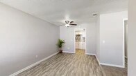 Located at 5327 Timuquana Rd in Jacksonville, Florida, this one-bedroom, two-bathroom unit offers a thoughtfully organized single-floor layout that maximizes every square foot. The living area greets you with durable wood-look vinyl flooring, neutral gray walls, a textured ceiling, and a ceiling fan that keeps the space comfortable year-round. Natural light filters in through slatted blinds on multiple windows, giving the interior a bright, airy feel. The kitchen is a standout feature, equipped with crisp white cabinetry, granite-look countertops, black appliances, and a striking mosaic tile backsplash that adds a modern touch to the space. The bedroom is finished with plush carpeting and a window that brings in natural light, creating a cozy retreat. Two closets provide practical storage throughout the unit. The two bathrooms are clean and functional — one features a full tub-shower combo with white tile surround, while the vanity area showcases a granite countertop with an undermount sink and a large mirror. The consistent use of neutral tones, updated finishes, and wood-look flooring throughout ties the entire space together into a cohesive and move-in-ready home.