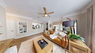 Located at 900 Legacy Park Dr in Lawrenceville, GA, this one-bedroom, one-bathroom residence offers a thoughtfully designed open-concept layout that maximizes its well-proportioned footprint. Rich hardwood-style flooring flows throughout the main living areas, anchoring a bright and cohesive interior palette of warm neutrals and crisp whites.

The living room serves as the heart of the home, featuring a ceiling fan, crown molding, and a distinctive built-in shelving unit that adds both character and functional storage. Large windows with blinds and linen drapes flood the space with natural light and offer views of lush greenery. The adjacent dining area, tucked in a sunny windowed nook, provides an intimate setting for meals.

The kitchen is equipped with stainless steel appliances, white shaker-style cabinetry, a subway tile backsplash, and a generous white countertop peninsula with an undermount sink — ideal for both cooking and casual dining. A skylight above adds additional natural brightness.

The primary bedroom is a calm, carpeted retreat with a ceiling fan and ample space. It is complemented by a walk-in closet outfitted with multi-tier wire shelving and hanging rods. The bathroom features a full tub-shower combination with white tile surround, a white vanity with a large mirror, and hardwood-style flooring.