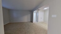 This single-floor, 2-bedroom, 1-bathroom residence offers a straightforward and functional layout designed for comfortable living. The floor plan connects a living area, kitchen, two bedrooms, a full bathroom, and a hallway in a cohesive arrangement.

The living area features neutral gray walls, wall-to-wall carpet, and a textured ceiling, creating a clean and understated atmosphere. It flows into the kitchen, which is equipped with gray cabinetry, a single-basin sink, a stainless steel refrigerator, and hard flooring — offering a practical cooking space with a clean, modern aesthetic.

The primary bedroom is a well-proportioned room with carpet flooring, a ceiling fan with integrated lighting, and a large window that brings in ample natural light along with views of surrounding greenery. A sliding glass door in one of the bedrooms opens to an outdoor area, adding a pleasant connection to the exterior. The second bedroom is a cozy, carpeted space with neutral walls and a textured ceiling.

The bathroom is well-appointed with a full tub and shower combo featuring white subway tile surround, hardwood flooring, a vanity with storage, and gray overhead cabinetry for additional organization.

Throughout the space, a consistent neutral color palette and carpet flooring provide a cohesive and move-in ready environment.