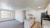 This single-floor unit offers a clean, modern aesthetic throughout, with thoughtful updates and a functional layout. The kitchen serves as a central highlight, featuring crisp white shaker-style cabinetry, granite countertops, a subway tile backsplash, a stainless steel undermount sink, and a full suite of stainless steel appliances including a refrigerator, range, microwave, and dishwasher. Light wood-look flooring runs through the kitchen and entryway, creating a warm and cohesive transition between spaces. The living area is carpeted and benefits from natural light through a window overlooking the surrounding neighborhood. The entry area provides convenient closet storage alongside the front door. Two bedrooms are finished with plush carpet and feature windows that invite natural light; one bedroom includes mirrored sliding closet doors, adding a sense of depth and brightness to the room. The bathroom is neatly appointed with large-format tile on both the floor and the tub surround, offering a clean and contemporary feel. Throughout the unit, crisp white walls, textured ceilings, and consistent trim work contribute to a bright, move-in-ready atmosphere.