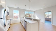 This efficiently designed 1-bedroom, 1-bathroom unit offers a clean, modern aesthetic throughout its single floor. The open-concept layout connects the living area to a well-appointed kitchen, which serves as the centerpiece of the space. The kitchen features a large peninsula with white quartz countertops, white shaker-style cabinetry, stainless steel appliances including a refrigerator, microwave, and dishwasher, and elegant pendant lighting hanging above. Multiple large windows surround the kitchen, inviting abundant natural light and offering views of the surrounding neighborhood's greenery and brick buildings. Light wood-tone flooring runs consistently throughout, complementing the crisp white walls and creating a warm yet contemporary feel. The bedroom is a comfortable, well-proportioned room equipped with a ceiling fan and a large window framing outdoor views. A notable feature of the bedroom is the dual closet system, providing generous storage with wire shelving and hanging rods. The full bathroom is finished in a clean, minimalist style with white shaker vanity cabinetry, a white quartz countertop, a large framed mirror, and a full tub-shower combination. The overall ambiance of the unit is bright, airy, and move-in ready, with consistent modern finishes throughout.