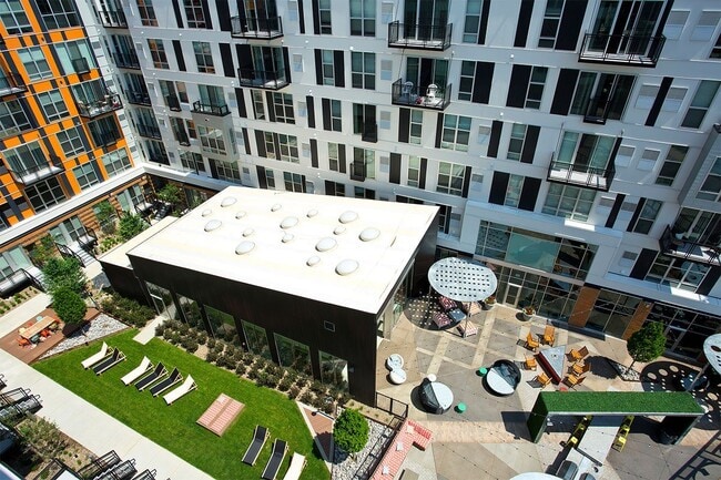 A modern building with a white roof and a green lawn in front. - Albion at Morrow Park