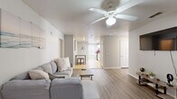 This well-appointed single-story home offers an impressive six bedrooms and four bathrooms, making it an ideal choice for large households or those seeking abundant space. The open living area features light wood-look flooring, neutral gray walls, and a ceiling fan, creating a bright and airy atmosphere that flows naturally toward the kitchen and hallway beyond.

The kitchen is outfitted with white cabinetry, granite-look countertops, tile flooring, and stainless steel appliances, including an electric range. A pantry provides additional storage, and a window brings in natural light. The dedicated laundry room includes a full-size washer and dryer, a built-in folding counter, shelving, and a bright window — a practical and functional space.

Each of the six bedrooms is finished with wood-look flooring and ceiling fans, with most featuring generous closet access — seven closets are distributed throughout the home. The primary bedroom offers a notably spacious footprint. The four bathrooms are consistently appointed with granite-top vanities, white cabinetry, tile flooring, and shower facilities. The overall design palette of soft whites and light grays lends a clean, cohesive feel to every room in this highly functional home.