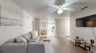 This well-appointed single-story home offers an impressive six bedrooms and four bathrooms, making it an ideal choice for large households or those seeking abundant space. The open living area features light wood-look flooring, neutral gray walls, and a ceiling fan, creating a bright and airy atmosphere that flows naturally toward the kitchen and hallway beyond.

The kitchen is outfitted with white cabinetry, granite-look countertops, tile flooring, and stainless steel appliances, including an electric range. A pantry provides additional storage, and a window brings in natural light. The dedicated laundry room includes a full-size washer and dryer, a built-in folding counter, shelving, and a bright window — a practical and functional space.

Each of the six bedrooms is finished with wood-look flooring and ceiling fans, with most featuring generous closet access — seven closets are distributed throughout the home. The primary bedroom offers a notably spacious footprint. The four bathrooms are consistently appointed with granite-top vanities, white cabinetry, tile flooring, and shower facilities. The overall design palette of soft whites and light grays lends a clean, cohesive feel to every room in this highly functional home.
