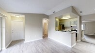 This single-story 2-bedroom, 2-bathroom residence offers a thoughtfully designed layout that maximizes functionality and comfort. The combined kitchen and living area forms the heart of the home, featuring durable wood-style flooring, neutral warm-gray walls, and a textured ceiling throughout. The kitchen is outfitted with light blue-gray cabinetry, white quartz-style countertops, stainless steel appliances including a refrigerator and range, and a peninsula that opens toward the living space—ideal for both casual dining and entertaining. The living room is bright and open, highlighted by a large sliding glass door that invites natural light and provides views of the surrounding outdoor greenery and pool area. Both bedrooms are comfortably sized, with the primary bedroom offering ample floor area, wood-style flooring, a ceiling fan with light fixture, and a window with exterior views. The second bedroom mirrors this layout. The two bathrooms are cleanly finished, each featuring gray vanity cabinetry, speckled countertops, and wood-style flooring. One bathroom includes a tub/shower combination, while the other features a shower with a bold geometric curtain. A hallway and closet complete the practical layout of this well-maintained residence.
