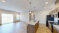 Located at 267 Seminole Rd in Norton Shores, MI, this well-appointed 2-bedroom, 2-bathroom single-floor home offers a thoughtfully designed layout with modern finishes throughout. The open-concept kitchen and living area serves as the heart of the home, anchored by a large center island with granite countertops, an undermount sink, and pendant lighting. Warm-toned wood cabinetry lines the kitchen walls, complemented by stainless steel appliances including a refrigerator, range, and microwave. Light wood-look flooring flows seamlessly through the main living area, enhancing the bright, airy ambiance. Sliding glass doors in the living area let in generous natural light and provide views of the lush greenery outside. The two bedrooms feature plush carpeting and dedicated closet space, with the primary bedroom offering a spacious walk-in closet with wire shelving. One bathroom includes a walk-in shower with clean white surround, while the second bathroom is combined with a convenient laundry area. A hallway connects the private spaces, and three closets throughout ensure ample storage. The overall design is clean and contemporary, ideal for comfortable everyday living.