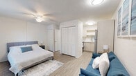 Located at 3600 Windmeadows Blvd in Gainesville, FL, this thoughtfully designed one-bedroom, one-bathroom unit makes excellent use of its compact footprint across a single floor. The space is unified by light hardwood-style flooring and a neutral white color palette throughout, creating a clean and cohesive aesthetic.

The generously sized primary bedroom serves as the heart of the unit, offering ample room for a full-size bed, a ceiling fan for comfort, a wall-mounted television, and a window-mounted AC unit. Natural light filters in through white-curtained windows, brightening the room, while a full-length mirror and entry door add functionality.

The living area flows naturally from the bedroom, featuring a teal sofa, framed wall art, and louvered bi-fold closet doors for storage. Flush-mount ceiling lighting keeps the space well-lit and practical.

The kitchen is well-appointed with light wood cabinetry, white countertops, a stainless steel refrigerator, an electric range, a microwave, and an undermount sink with a modern pull-down faucet — offering full cooking capability in a compact, U-shaped layout.

The bathroom is clean and functional, finished in white with a bathtub/shower combo, a vanity with mirror, and wood-style flooring consistent with the rest of the unit.