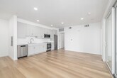 Located in the Mid-City neighborhood of Los Angeles, this thoughtfully designed one-bedroom, one-bathroom residence offers a clean, modern aesthetic throughout. Light-toned hardwood flooring flows seamlessly across the open-plan living and dining areas, complemented by crisp white walls and recessed lighting that create a bright, airy atmosphere. The spacious living room opens directly onto a private balcony through floor-to-ceiling sliding glass doors, inviting natural light and outdoor views of the surrounding neighborhood, including mature trees and palm-lined streets. A second living area connects to a well-appointed kitchen featuring white cabinetry, stone countertops, a stainless steel dishwasher, and ample storage. The generously sized bedroom is bathed in natural light from a large picture window overlooking lush greenery, offering a calm and private retreat. A dedicated closet provides convenient storage. The bathroom is finished in a contemporary style with a white vanity, integrated sink, a walk-in tiled shower, and coordinating cabinetry. Clean lines, a neutral palette, and quality finishes define the overall character of this well-planned residence.