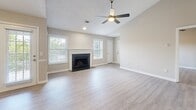 Located on Carothers Pkwy in Franklin, TN, this single-story home offers a well-designed, open layout finished with light hardwood-style flooring throughout. The living area is a welcoming focal point, centered around a classic tile-surround fireplace with a white mantel, flanked by multiple windows that invite generous natural light. A ceiling fan overhead adds both comfort and style to the space.

The kitchen features gray shaker-style cabinetry, a marble-look tile backsplash, light quartz countertops, a breakfast bar peninsula, and stainless steel appliances including a refrigerator and microwave. A nearby closet provides additional storage convenience.

The bedrooms are comfortably proportioned, each equipped with ceiling fans and windows offering views of the surrounding greenery. One bedroom benefits from vaulted ceilings, adding an airy, elevated feel, while another enjoys a corner window configuration that enhances natural light. An en-suite bathroom is accessible directly from one of the bedrooms.

The bathroom is fitted with hardwood-style flooring, a tub-shower combo with white tile surround, a dark vanity, and a tall slate-blue storage cabinet for added organization. A separate entry area with a glass-paneled door and sidelight windows creates a bright, welcoming entryway into the home.