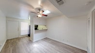 Located at 2212 San Gabriel St in Austin, TX, this single-floor unit offers a practical and functional layout designed for comfortable everyday living. The main living area is bright and open, featuring light wood-style flooring, crisp white walls, and a ceiling fan with a built-in light fixture. A notable skylight above the living space brings in natural light, enhancing the airy feel of the room. A pass-through counter connects the living area to the kitchen, which is equipped with warm wood cabinetry, a granite-style countertop, a double stainless steel sink, and black appliances including an electric range and an over-the-range microwave. The kitchen also features matching wood-style flooring that ties seamlessly into the living space. The bedroom is generously sized with plush carpeting, a ceiling fan, a large window for natural light, and a full-width closet with bi-fold doors offering ample storage. The bathroom is clean and functional, finished with white tile surrounding a tub-shower combination, a single vanity with white cabinetry, and a large mirror. The unit's straightforward, single-level layout and neutral palette make it a versatile and move-in-ready space in the heart of Austin.