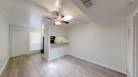 Located at 2212 San Gabriel St in Austin, TX, this single-floor unit offers a practical and functional layout designed for comfortable everyday living. The main living area is bright and open, featuring light wood-style flooring, crisp white walls, and a ceiling fan with a built-in light fixture. A notable skylight above the living space brings in natural light, enhancing the airy feel of the room. A pass-through counter connects the living area to the kitchen, which is equipped with warm wood cabinetry, a granite-style countertop, a double stainless steel sink, and black appliances including an electric range and an over-the-range microwave. The kitchen also features matching wood-style flooring that ties seamlessly into the living space. The bedroom is generously sized with plush carpeting, a ceiling fan, a large window for natural light, and a full-width closet with bi-fold doors offering ample storage. The bathroom is clean and functional, finished with white tile surrounding a tub-shower combination, a single vanity with white cabinetry, and a large mirror. The unit's straightforward, single-level layout and neutral palette make it a versatile and move-in-ready space in the heart of Austin.