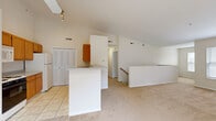 Located at 842 Cobblestone Circle in Painesville, Ohio, this two-bedroom, two-bathroom two-story residence offers a well-designed layout across two levels. The main level commands attention with soaring vaulted ceilings and an open-concept design that seamlessly connects the kitchen and living areas. The kitchen is equipped with warm wood cabinetry, a gas range, refrigerator, and microwave, and opens to a central breakfast bar with a light countertop — ideal for casual dining. Track lighting above enhances the bright, airy atmosphere. The expansive carpeted living room features a ceiling fan and provides access to a private balcony through sliding glass doors, while a fireplace mantle adds a classic touch. A dedicated laundry room with washer and dryer hookups and an electrical panel is conveniently located on this floor. Upstairs, the primary bedroom is generously sized with vaulted ceilings and walk-in closet space outfitted with wire shelving. The second bedroom features a double-door closet and neutral carpet. Both bathrooms include tile flooring, wood vanities, and tub/shower combinations. Six closets throughout provide ample storage. Carpet flows through the living and bedroom areas, while tile anchors the kitchen and bathrooms.