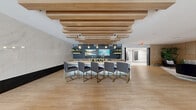 Located at Park Meadows Drive in Lone Tree, Colorado, this coworking clubroom and gameroom offers a generously sized, single-floor amenity space designed for both productivity and social engagement. The interior showcases a sophisticated modern aesthetic, blending warm natural wood tones with deep navy blue accents, brass fixtures, and light hardwood flooring throughout.

The centerpiece of the space is a striking wet bar and kitchen area featuring a dramatic marble-topped island, a blue mosaic tile backsplash, open wood shelving, dual wall-mounted TVs, and an eye-catching slatted wood ceiling treatment with pendant globe lighting — ideal for entertaining and casual gatherings. Adjacent to this, a lounge area provides plush velvet seating arranged around a sculptural brass coffee table, anchored by a textured accent wall and mounted display screen.

Dedicated coworking zones offer a variety of seating options, including semi-private booth-style nooks framed by dark wood columns with pendant lighting, banquette seating with marble-top tables, and intimate café-style tables with upholstered chairs. A private conference room accommodates small meetings, furnished with a round marble table, leather chairs, and curated wall art. Slatted wood partitions and bold wallcoverings add architectural interest, while large exterior-facing doors invite natural light into the space.