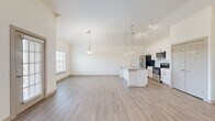 This thoughtfully designed 2-bedroom, 2-bathroom residence offers a bright and modern living experience across a single floor. The open-concept living and kitchen area is anchored by soaring vaulted ceilings that create an expansive, airy atmosphere. Large windows throughout flood the space with natural light, while a ceiling fan and pendant lighting add both function and style to the living area, which also features a private exterior door.

The kitchen is a standout feature, showcasing white shaker cabinetry, a subway tile backsplash, granite countertops, stainless steel appliances, and a central island with a built-in sink — ideal for both cooking and casual dining. Sleek light-toned hardwood-style flooring runs throughout the main living areas.

Both bedrooms are generously sized, carpeted for comfort, and equipped with ceiling fans and windows offering outdoor views. The spacious primary bedroom includes its own dedicated closet. Each bathroom reflects a clean, modern aesthetic — one features a walk-in glass shower with white subway tile and a granite vanity, while the second includes a full subway-tiled tub/shower combo. Two closets provide ample storage throughout the residence.