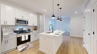 Located at 22100 E Quincy Ave in Aurora, CO, this well-designed one-bedroom, one-bathroom residence offers a thoughtfully laid-out single-floor plan with a clean, modern aesthetic. Light-toned luxury vinyl plank flooring runs throughout the entire space, creating a cohesive and bright atmosphere.

The kitchen is a standout feature, showcasing white shaker-style cabinetry, a hexagonal tile backsplash, and a full suite of stainless steel appliances including an electric range, over-the-range microwave, and a side-by-side refrigerator with ice maker. A central island with a white countertop and deep undermount sink anchors the kitchen, illuminated by stylish pendant lights with matte black and brass fixtures. The kitchen flows seamlessly into the dining area and living room, enhancing the open-concept feel.

The bedroom is a comfortable, light-filled retreat with a ceiling fan, a large window offering natural light, and access to two closets for ample storage. The bathroom is finished with large-format gray tile on the walls and surround, a soaking tub with shower, a white vanity, and wood-look flooring. Additional practical spaces include a dedicated laundry area and a utility room. The unit's clean white walls and modern black hardware details lend a cohesive, contemporary character throughout.