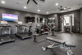 Located at 3040 S Fork Blvd in Idaho Falls, Idaho, this fitness center offers a comprehensive workout facility designed with both functionality and modern aesthetics in mind. The single-floor space is finished with dark charcoal-toned walls and durable rubberized flooring, creating a focused, energizing atmosphere throughout.

The facility is thoughtfully organized to accommodate a wide range of training styles. Cardio equipment, including multiple Spirit-brand treadmills and a rowing machine, lines one side of the space, while a dedicated strength training area houses cable and functional trainer machines, a Smith machine, and adjustable benches. A full dumbbell rack provides a complete free weight selection, and large wall-mounted mirrors amplify the sense of space and allow for form checks during workouts.

Overhead, large multi-blade ceiling fans ensure consistent airflow, complementing the recessed lighting that keeps the space bright and well-illuminated. Natural light enters through several windows, adding to the open, welcoming feel. A wall-mounted flat-screen television provides entertainment for cardio sessions.

Additional amenities include a water fountain station near the entry and a plyo box for functional training. Double glass doors offer easy access, and clearly posted fitness center rules and Wi-Fi information are visible near the entrance, ensuring a convenient and organized experience for all users.