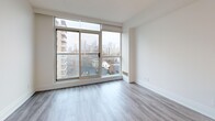Located at 50 Spadina Rd in Toronto's Annex neighbourhood, this two-level, 1-bedroom, 2-bathroom unit offers a well-organized layout split evenly across two floors, connected by a white-railed staircase. Light hardwood-style flooring runs throughout, complementing the crisp white walls and clean aesthetic.

The main level features an entrance with a hallway leading into an open-concept combined dining and living area, flooded with natural light through floor-to-ceiling windows that frame sweeping views of the Toronto skyline and surrounding neighbourhood. The modern kitchen is outfitted with white shaker cabinetry, a grey quartz peninsula with a double undermount sink, subway tile backsplash, and stainless steel appliances including a range, over-the-range microwave, dishwasher, and refrigerator. A full bathroom and in-unit laundry are also found on this level.

The upper floor hosts the private bedroom, a versatile den, a second full bathroom with white tile flooring and vanity, and four closets offering generous storage. The bedroom features a mirrored sliding closet and a window with city views. Both bathrooms are finished in clean white tones with chrome fixtures. The overall ambiance is bright, functional, and modern throughout.