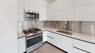 Located at 11036 Moorpark St in the Studio City neighborhood of Los Angeles, this modern single-floor residence offers a clean, contemporary design throughout. The open living and kitchen area is bathed in natural light from a large sliding glass door that leads to a private balcony overlooking lush, tree-lined surroundings. Track lighting overhead and light wood-toned flooring give the living space a bright, welcoming feel.

The kitchen is thoughtfully designed with high-gloss white cabinetry extending to the ceiling, a stainless steel backsplash, quartz countertops, and a full suite of stainless steel appliances including a gas range, built-in microwave, and a French door refrigerator — all contributing to a sleek, modern aesthetic.

The bedrooms feature the same light wood flooring, clean white walls, and large windows that frame open views of the surrounding neighborhood and distant hillsides, filling each room with abundant natural light.

The bathrooms are finished in a crisp, minimalist style with light wood flooring, tile-surround soaking tubs, chrome fixtures, and white vanities. The primary bathroom includes a wide illuminated mirror and an extended double-sink vanity, adding a refined, spa-like quality to the space. Every detail of this residence reflects a commitment to modern, functional living in one of Los Angeles' most sought-after neighborhoods.