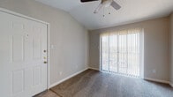 This single-floor unit offers a thoughtfully designed layout with a blend of comfort and modern finishes throughout. The living area makes a strong first impression with its vaulted ceiling and ceiling fan, creating a sense of openness and airflow. Plush carpeting covers the main living and bedroom spaces, while light wood-tone flooring runs through the kitchen and transitional areas. A large sliding glass door fitted with vertical blinds floods the living area with natural light and provides access to an outdoor space.

The kitchen is efficiently arranged and features gray cabinetry, white countertops, a peninsula with a built-in sink, and a full suite of stainless steel appliances including a refrigerator and electric range. A flush-mount ceiling light keeps the kitchen bright and functional.

The bedroom is a calm, neutral retreat with soft carpeting, a ceiling fan, and a spacious closet. An additional room with hardwood-style flooring connects to the rest of the unit with easy flow.

The bathroom is clean and contemporary, showcasing gray cabinetry, a marble-look vanity countertop, a large mirror, and a full tub-shower combination with white tile surround. Light wood-tone flooring ties the bathroom's aesthetic together cohesively. Overall, the unit presents a neutral, modern palette throughout.
