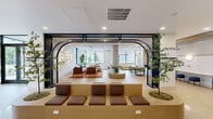 Located on Atlantic Street in Plainfield, NJ, this thoughtfully designed single-floor amenity space offers a generous and versatile layout finished with contemporary architectural detail. The main lobby welcomes visitors with light hardwood flooring, floor-to-ceiling glass walls, and a revolving entry door that floods the interior with natural light and views of the surrounding streetscape. Potted trees and curated greenery add warmth to the bright, open atmosphere.

The primary lounge areas are defined by bold design choices, including a striking sculptural chandelier with branching arms and globe accents, complemented by an artistic wall-mounted light installation. Seating arrangements feature a mix of rich leather armchairs, curved sofas, and patterned rugs, all anchored beneath high ceilings. A dramatic arched black metal structural element serves as a visual divider between zones, adding industrial character to the refined interior.

A dedicated media lounge offers a more intimate atmosphere, with a dark, moody palette, plush upholstered seating, patterned ottomans, and a large flat-screen display framed by floor-length drapes — ideal for private screenings or social gatherings. An adjacent lounge nook features tiered built-in seating along a textured tile wall beside a large window overlooking the street. Throughout, the design balances openness with defined social zones, creating a dynamic and functional communal environment.