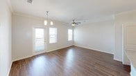 This single-floor residence offers a thoughtfully designed layout with a clean, modern aesthetic throughout. The kitchen is a functional centerpiece, featuring dark espresso cabinetry, granite-style countertops, and a full suite of stainless steel appliances including a refrigerator, electric range, and built-in microwave. A convenient in-unit laundry closet with a full-size washer and dryer is located directly adjacent to the kitchen. Rich hardwood-style flooring flows through the main living areas, complemented by crown molding that adds a refined touch. The living area is open and bright, benefiting from multiple windows that invite natural light, a ceiling fan, and pendant lighting above. A door leads to an outdoor balcony or patio area. The bedrooms are carpeted for comfort, each fitted with ceiling fans and windows overlooking the outdoors. One bedroom includes built-in shelving and a desk nook, ideal as a home office or study space. The bathroom features a granite-topped vanity with dark cabinetry, wood-style flooring, and a tiled soaking tub and shower combination. The overall ambiance is clean, neutral, and move-in ready, with consistent finishes tying the space together cohesively.