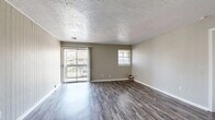 Located at 301 Hal Muldrow Dr in Norman, Oklahoma, this two-bedroom, two-bathroom residence offers a well-organized single-floor layout designed for comfortable everyday living. The living room serves as the heart of the home, featuring durable hardwood-style plank flooring, a textured ceiling, a vertical shiplap accent wall, and a sliding glass door that opens to a private balcony, allowing natural light to fill the space. A secondary window further brightens the room. The kitchen is thoughtfully appointed with white cabinetry, gray laminate countertops, black appliances including an electric range and refrigerator, and a stylish mosaic tile backsplash that adds a decorative touch. Light tile flooring completes the kitchen's clean, functional aesthetic. The generously sized primary bedroom provides ample space, continuing the hardwood-style flooring found throughout the home. Both bathrooms feature tile flooring, white vanities with under-sink storage, wall mirrors, and tub-shower combinations. A hallway and dedicated closet offer additional storage and connectivity between rooms. Neutral gray wall tones and consistent finishes throughout create a cohesive, move-in-ready ambiance suited for a variety of lifestyles.