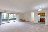 Located at 13206 Twinbrook Pkwy in Rockville, MD, this single-floor, 2-bedroom, 1-bathroom residence offers a well-organized layout with a practical mix of shared and private spaces. The combined living and dining area is generously proportioned, featuring plush wall-to-wall carpeting, neutral walls, and large sliding glass doors that open to a balcony, flooding the room with natural light and providing views of the surrounding greenery. A pendant light fixture marks the transition toward the adjacent kitchen. The kitchen is equipped with warm oak cabinetry, granite-style countertops, a gas range, refrigerator, and a double sink, all set on durable tile-style flooring. The primary bedroom is spacious, with a broad window overlooking the courtyard and lush evergreen trees. The second bedroom offers a similar layout with a window framing outdoor views. A versatile den provides additional flexible space. The full bathroom features classic white subway tiling accented by a bold black-and-white checkered border, a soaking tub, and tile flooring. Storage is a standout feature, with five closets throughout — including a large walk-in with built-in shelving and hanging rods. A hallway connects the living areas to the private quarters, completing the functional floor plan.