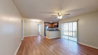 Located at 3024 N Powers Dr in Orlando, FL, this 2-bedroom, 2-bathroom residence offers a well-organized single-floor layout designed for comfortable everyday living. The open-concept living and kitchen area serves as the heart of the home, featuring wood-look flooring throughout and a ceiling fan with light fixture overhead. A sliding glass door fills the living area with natural light and provides views of the outdoors. The kitchen is equipped with stainless steel appliances — including a refrigerator, range, and over-the-range microwave — warm-toned wood cabinetry, dark granite-style countertops, and a peninsula that offers additional prep and seating space. Both bedrooms are bright and well-proportioned, each featuring ceiling fans, wood-look flooring, and ample closet space. The primary bedroom includes a generously sized walk-in closet with wire shelving. The two bathrooms are clean and functional, each featuring a single-sink vanity with wood cabinetry, a tub/shower combination with white tile surround, and wood-look flooring. A dedicated laundry area adds everyday convenience. Neutral tones and textured ceilings are consistent throughout, creating a cohesive and move-in ready atmosphere.
