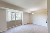 Located on Red Top Rd in Takoma Park, MD, this two-bedroom, one-bathroom residence offers a well-organized single-floor layout designed for comfortable everyday living. The combined living and dining area is generously proportioned, featuring wall-to-wall carpeting, neutral beige tones, and large windows that frame lush, tree-lined outdoor views, filling the space with abundant natural light. A pendant light fixture anchors the dining area, adding a subtle decorative touch. The kitchen is efficiently arranged in a galley-style configuration, equipped with light wood cabinetry, dark granite-style countertops, black appliances including a range and refrigerator, and tile flooring. A pass-through view connects the kitchen directly to the living area, enhancing the open feel. The primary bedroom offers a comfortable footprint with a set of bi-fold closet doors and a window overlooking greenery. The second bedroom is similarly carpeted and bright, with direct hallway access. The bathroom features a wood-toned vanity with a wide mirror and clean white fixtures. With four closets distributed throughout, storage is a practical strength of this layout. The overall ambiance is calm, clean, and move-in ready.