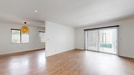 Located in the heart of Los Angeles, this 2-bedroom, 1-bathroom single-story home offers a well-designed layout with consistent wood-style flooring throughout. The spacious living room is bright and open, featuring recessed lighting, clean white walls, and a sliding glass door fitted with vertical blinds that invites natural light and provides outdoor access. The kitchen is a functional highlight of the home, outfitted with rich dark wood cabinetry, granite-style countertops, stainless steel appliances including a gas range and dishwasher, and a double basin sink positioned beneath a window. The generous primary bedroom includes a ceiling fan with light fixture, a wall-mounted AC unit, and large windows with vertical blinds that allow ample natural light. The second bedroom features wainscoting along the lower walls, dual windows, and its own wall AC unit. The bathroom has a retro-inspired aesthetic with pink-accented tile wainscoting, a white double vanity with pink sink basins, and a frosted privacy window. Two hallways connect the rooms efficiently throughout the single-floor layout, contributing to a cohesive and navigable flow. The home offers a comfortable and functional living environment in a well-situated Los Angeles neighborhood.