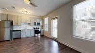 Located at 916 Joseph E Lowery Blvd NW in Atlanta's vibrant West Side, this single-floor residence delivers a clean, modern aesthetic throughout. Rich, dark hardwood-style flooring flows seamlessly across the open living and kitchen areas, anchored by ceiling fans that enhance airflow and comfort.

The kitchen is a functional centerpiece, outfitted with gray shaker cabinets, granite countertops, and a classic white subway tile backsplash. A full suite of stainless steel appliances — including a refrigerator, electric range, over-the-range microwave, and dishwasher — ensures a well-equipped cooking space. Natural light pours in through multiple windows, and a glass-panel door provides direct access to a private exterior balcony or entry area.

The living space benefits from an open layout with a distinctive pass-through architectural detail that connects areas while maintaining a sense of definition. A sliding barn door adds a stylish, modern-industrial touch to the interior corridor.

The bathroom is thoughtfully finished with hexagonal white floor tile, a subway-tiled tub surround, a granite-topped vanity with brushed gold fixtures, and a large framed mirror. In-unit laundry is a practical highlight, with a stacked washer and dryer conveniently housed within the hallway. The overall design balances contemporary finishes with everyday functionality.