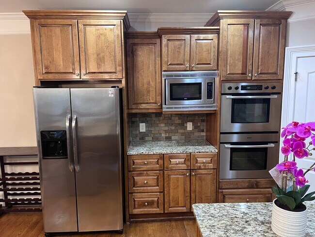 Kitchen - Kitchen featuring dark hardwood / wood-style flooring, appliances with stainless steel fin - 7987 Magnolia Sq
