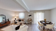 Located at 722 S Dargan St in Florence, South Carolina, this single-story residence offers a thoughtfully arranged layout with a warm, neutral aesthetic throughout. The open-concept living and dining area serves as the heart of the home, highlighted by a distinctive beam detail along the ceiling, light hardwood-style flooring, and an abundance of natural light streaming through multiple windows dressed with sheer white curtains. The living area provides generous space for seating arrangements, while the adjacent dining area comfortably accommodates a round dining table and chairs, creating a seamless flow between the two zones.

A separate room off the main living area offers additional flexible space, complete with a closet featuring louvered doors and direct access to a full bathroom equipped with a tub-shower combination and safety grab bar. The kitchen is efficiently designed with white cabinetry, a full-size refrigerator, electric range, and ample counter space. The bedroom is a calm retreat with a window for natural light and direct access to a private bathroom featuring a vanity with mirror and medicine cabinet. Consistent hardwood-style flooring and a soft, neutral color palette unify the space throughout.