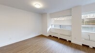 Located at 77 Parkwoods Village Dr in Toronto's Parkwoods-Donalda neighbourhood, this efficiently designed single-floor unit offers a thoughtfully organized layout comprising an open-concept kitchen and living area, along with one full bathroom. The interior presents a clean, contemporary aesthetic characterized by crisp white walls, smooth ceilings, and warm hardwood-style flooring that runs throughout the main living space.

The kitchen is a standout feature, equipped with stainless steel appliances including a range, built-in microwave, dishwasher, and refrigerator. White shaker-style cabinetry is complemented by a subtle tile backsplash, while a generous peninsula with a dark quartz countertop and integrated sink provides both prep space and a casual dining option. Track lighting overhead ensures the kitchen is well-illuminated.

The living area benefits from multiple large windows fitted with baseboard heating units beneath, allowing natural light to filter in alongside views of surrounding greenery. The space feels open and airy despite its compact footprint.

The bathroom is finished with neutral large-format floor tiles, a dark wood vanity, and a full tub-shower combination enclosed by white subway tile from floor to ceiling, maintaining the unit's consistent modern and clean design throughout.