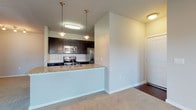 This single-floor, 2-bedroom, 2-bathroom residence offers a thoughtfully designed open layout that seamlessly connects the living and kitchen areas. The kitchen is a standout feature, showcasing dark espresso cabinetry with brushed nickel hardware, granite countertops, a white subway tile backsplash, and a full suite of stainless steel appliances including a French door refrigerator, electric range, built-in microwave, and dishwasher. A peninsula with a granite countertop and an undermount sink serves as both a functional workspace and casual dining area, accented by stylish pendant lighting overhead. The open living area features plush carpeting and a ceiling fan, creating a comfortable, welcoming atmosphere. Rich wood-tone flooring runs through the kitchen and bathrooms, providing a warm contrast to the neutral walls throughout. Both bathrooms are finished consistently with dark cabinetry, granite vanity tops, undermount sinks, and tile surrounds. The bedrooms are generously sized, carpeted, and filled with natural light from multiple windows with white blinds. Ceiling fans in the bedrooms add to the comfort of each room. The overall design palette is clean and contemporary, with neutral tones and quality finishes that create a cohesive, move-in-ready environment.