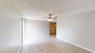Located in Long Beach, Mississippi, this single-floor, 2-bedroom, 2-bathroom unit offers a practical and comfortable layout designed for easy living. The open living area features light wood-look flooring, neutral gray walls, a textured ceiling, and a ceiling fan with integrated lighting, creating a bright and airy atmosphere. A sliding glass door with vertical blinds floods the space with natural light and provides access to the outdoors. The living area connects seamlessly to a separate dining space, which is accented by a pendant light fixture overhead. The galley-style kitchen is well-appointed with white shaker-style cabinetry, speckled countertops, a skylight for added brightness, and black appliances including a range, microwave, and dishwasher — with light wood-look flooring continuing throughout. Both bedrooms are generously proportioned, featuring ceiling fans, neutral tones, and wood-look flooring, with one bedroom offering a window with blinds for natural light. Each of the two bathrooms includes a wide vanity with speckled countertops, a large mirror, and a shower-tub combination, with brushed nickel grab bars adding a practical touch. The unit's cohesive finishes and single-level layout make it a functional and move-in-ready space.