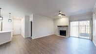 This single-floor home offers five bedrooms and two full bathrooms within a thoughtfully designed layout. The open-concept kitchen and living room serve as the heart of the home, anchored by a striking tile-surround fireplace with a wood mantel and complemented by a ceiling fan with light. Sliding glass doors in the living area bring in natural light and offer outdoor access. The kitchen is outfitted with crisp white shaker cabinetry, a classic subway tile backsplash, stainless steel appliances including a refrigerator, microwave, and range, and a generous white quartz peninsula with a built-in sink. Industrial-style pendant lights hang above, adding a modern touch. Dark hardwood-style flooring flows through the main living areas, transitioning to warm, plush carpet in the bedrooms. The primary bedroom is a comfortable retreat, accented with crown molding and multiple access points. The secondary bedrooms feature neutral walls, natural light from window blinds, and ceiling fans. The bathrooms are finished with white cabinetry, quartz countertops, and a glass-enclosed shower. A dedicated laundry area, hallway, and closet round out the functional floor plan of this well-maintained home.