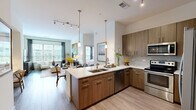 Located at 4150 Ashford Dunwoody Rd NE in Brookhaven, GA, this 2-bedroom, 3-bathroom residence offers a thoughtfully designed open-concept layout. The modern kitchen serves as the heart of the home, featuring an L-shaped island with a double sink, crisp white quartz countertops, warm wood-toned cabinetry, a tile backsplash, and stainless steel appliances including a range, microwave, and dishwasher. The kitchen flows seamlessly into the dining and living areas, which are bathed in natural light from large windows dressed with plantation shutters and floor-to-ceiling curtains. Light wood-style flooring runs throughout, enhancing the bright and airy atmosphere. The living room offers comfortable proportions and outdoor views. A hallway connects the social spaces to the private quarters, passing by a well-appointed bathroom. The primary bedroom features a wide window wall, a walk-in closet with wire shelving systems, and an en-suite bathroom with a soaking tub, marble-style tile surround, and brushed gold fixtures. The second bedroom is equally well-lit with ample closet storage. Three full bathrooms ensure convenience for residents and guests alike, completing this polished and functional Brookhaven home.